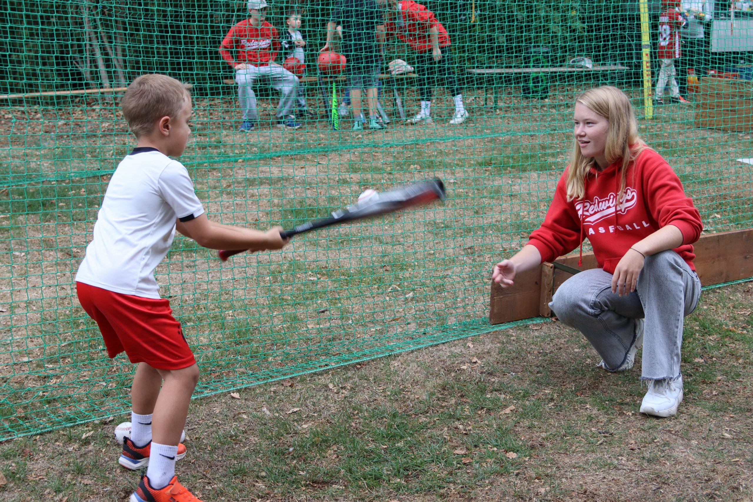 Redwings-Helferin unterstützt ein Kind beim Schlagen