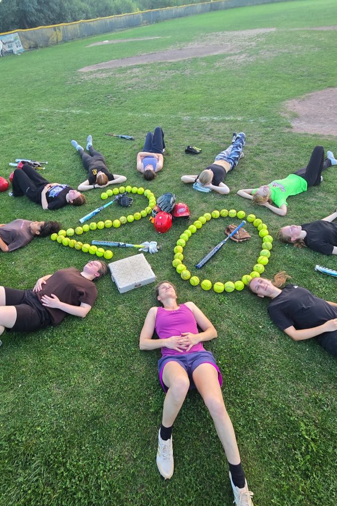 Redwings-Spielerinnen liegen um eine aus Softballs geformte 20 auf dem Baseballfeld